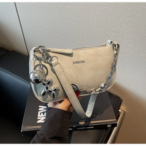 Détail du sac beige avec chaîne en argent et breloque artistique en forme de chien ballon