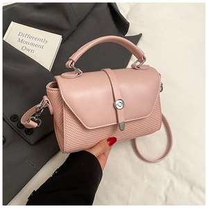 Détail du sac bandoulière rose clair avec texture tressée, fermoir argenté et poignée