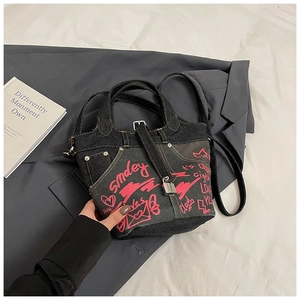 Detail of blue denim bucket bag with pink graffiti print and metal padlock accessory