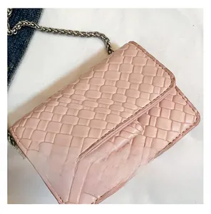Detailed view of pink woven texture and silver chain strap on a mini crossbody bag