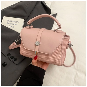 Détail du sac rose avec rabat en cuir, texture tissée et boucle métallique ronde