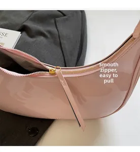 Detail of pink patent leather moon bag featuring smooth gold metal zipper and fabric lining