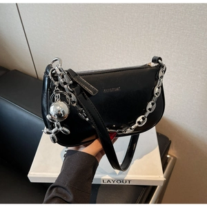 Détail du sac lune en cuir noir brillant avec chaîne argentée et breloque chien
