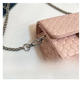 Detail view of pink woven mini bag with silver chain strap and metal lobster clasp hardware