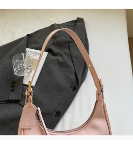 Detail of light pink leather hobo bag with gold hardware and logo tag on grey blazer
