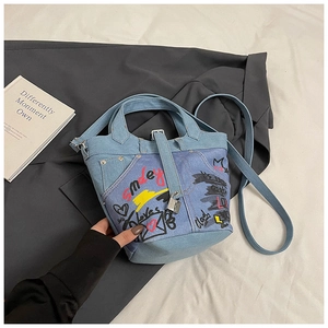 Detail of blue denim bucket bag with colorful graffiti prints and a metal lock pendant