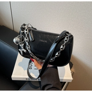 Détail du sac à bandoulière en cuir noir brillant avec chaîne argentée et pendentif