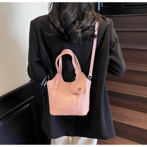 Pink lychee texture tote bag with leaf charm shown on model in a modern staircase setting