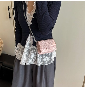 Close-up of pink woven mini crossbody bag with silver chain strap on model