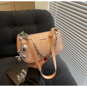 Détail du sac sous l'aisselle rose avec chaîne argentée et breloque chien