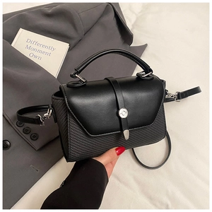 Gros plan sur sac bandoulière noir avec texture tressée, rabat cuir et boucle argentée