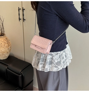Close-up of pink mini crossbody bag with textured leather and metal chain strap