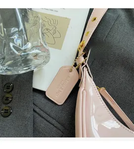 Detail of pink patent leather handbag with gold chain and branded designer tag