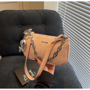 Détail du sac baguette orange clair avec chaîne argentée et breloque chien ballon