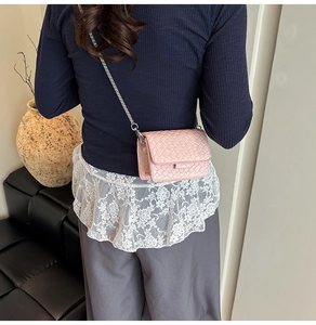 Pink woven leather mini crossbody bag with silver chain strap shown from a back view