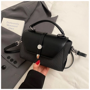 Détail du sac bandoulière noir avec rabat en cuir lisse et contraste de texture tissée