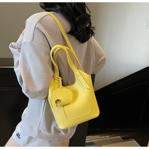 Detail of yellow lychee leather bucket bag with cute elephant charm on shoulder