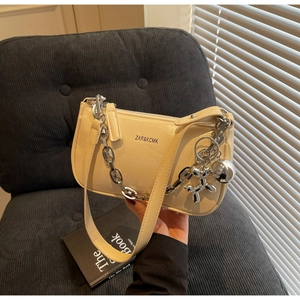 Détail du sac à main beige en similicuir avec chaîne argentée et pendentif chien ballon