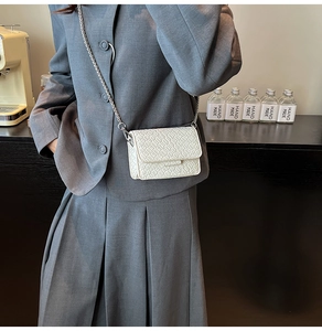 Macro shot of white woven mini bag texture and slim silver metal chain strap detail
