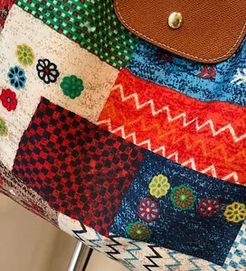 Detail van levendige patchwork stof en bruine lederen klep met gouden drukknoopsluiting