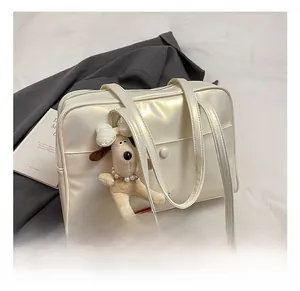 Detail of cream white faux leather tote bag with plush dog charm and pearl texture