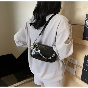 Gros plan d'un sac à bandoulière noir brillant avec chaîne argentée et charm chien