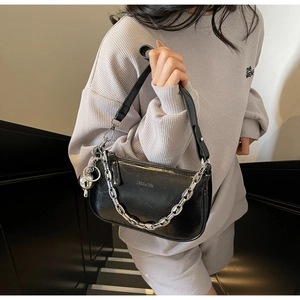 Détail d'un sac d'épaule en cuir noir brillant avec chaîne argentée et charme sphère