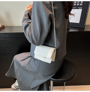 Detailed view of mini white woven crossbody bag with silver chain strap on model