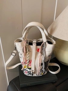 White canvas bucket bag with red smile graffiti and adjustable straps in home setting