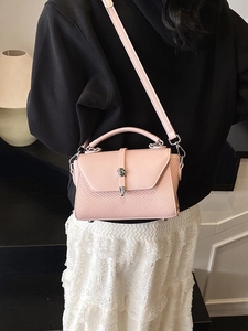 Sac bandoulière rose avec texture tressée et fermoir bouton argenté sur mannequin