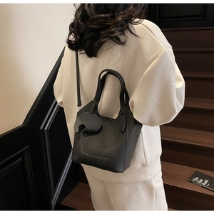 Detail of black lychee grain leather bucket bag with decorative leaf charm and strap