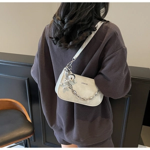 Détail du sac à épaule en cuir blanc cassé avec chaîne argentée et breloque chien ballon