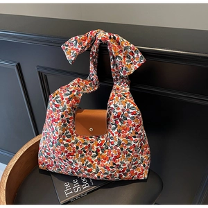Bloemen canvas draagtas met lederen flap en grote strik schouderband op een stoel