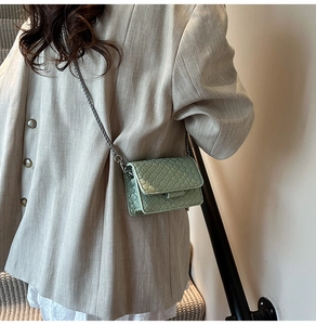 Detail view of mint green woven crossbody bag with metallic chain strap on model