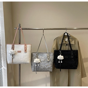 Detailed close-up of textured faux-leather tote bags with creative plush cloud pendants