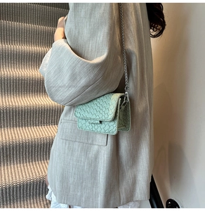 Detail of mint green woven mini crossbody bag featuring a silver metal chain strap