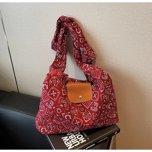 Detail van rode paisley canvas draagtas met bruine lederen flap en metalen drukknop