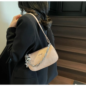 Détail du sac hobo en cuir mat beige avec chaîne argentée et pendentif boule métallique