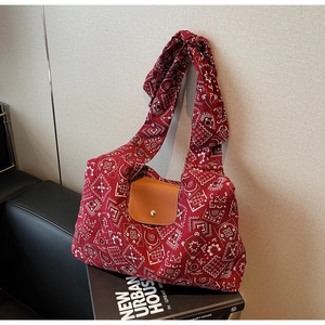 Detailopname van canvas shopper met rood paisley-patroon en bruine lederen klep met metalen gesp