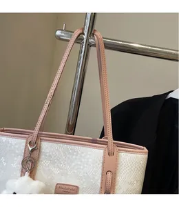 Detail of white snakeskin texture tote bag with pink leather strap and brand label