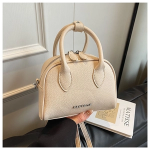 Close-up of off-white lychee pattern leather bowling bag with silver zipper and logo