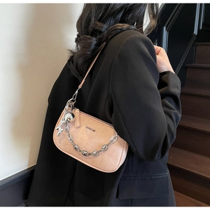 Sac demi-lune pêche avec chaîne argentée et breloque sur une veste de blazer