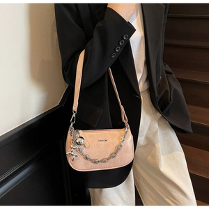 Détail du sac baguette rose avec chaîne argentée et breloque chien ballon sur modèle