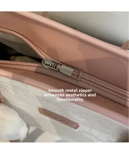 Close-up of silver metal zipper and brand logo on pink faux leather and snakeskin bag