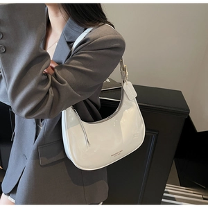 Close-up of a white patent leather hobo bag worn with a gray blazer for a stylish look