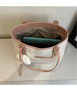 Top view of spacious snakeskin tote bag interior holding a tablet and plush charm