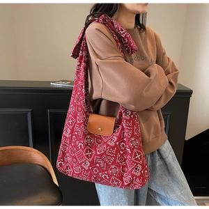 Detail van de rode canvas shopper met paisleyprint en leren klep gedragen door een model