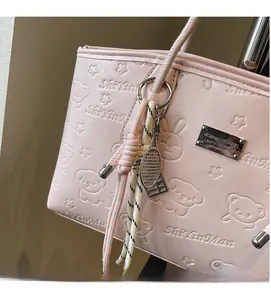 Close-up of pink leather tote bag with embossed cartoon patterns and metal nameplate