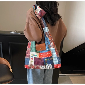 Detail van de patchwork canvas tas met bruine lederen flap en metalen drukknop
