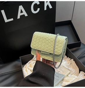 Detail of mint green woven crossbody bag with silver chain strap and flap closure